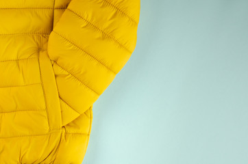 Yellow kids winter jacket composition on blue background.