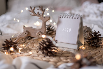 New Year 2020 calendar with lights on rustic server with cones and toys