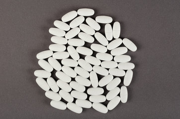 White medical pills composition on dark background.
