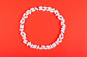 White medical pills composition on red background.