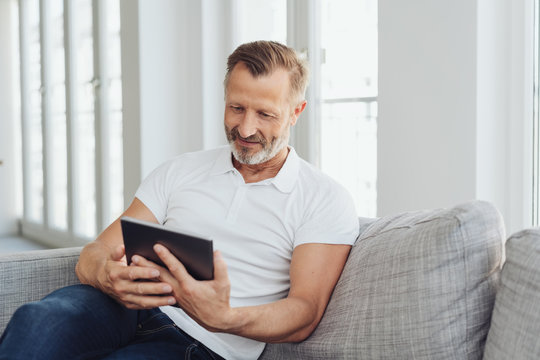 Man relaxing at home with his tablet pc