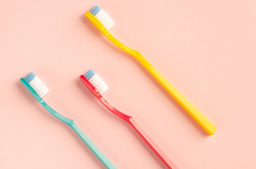 Colored toothbrushes composition on pink background. Flat lay.