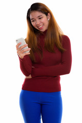 Fototapeta premium Studio shot of young Asian woman with turtleneck sweater using phone