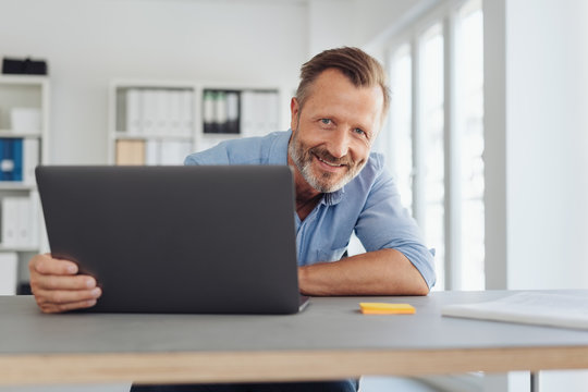 Smiling confident businessman seated at a desk