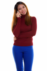 Studio shot of young Asian woman with turtleneck sweater using phone