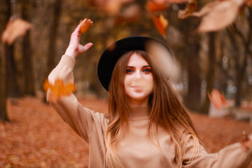 Autumn girl in the park. Sweater, hat and leather skirt. Stylish image. Atmosphere. Makeup