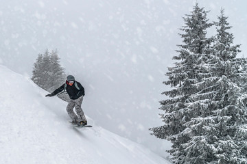 Snowboarder rides from powder snow hill. Mountain freeride snowboarding. Winter Carpathians