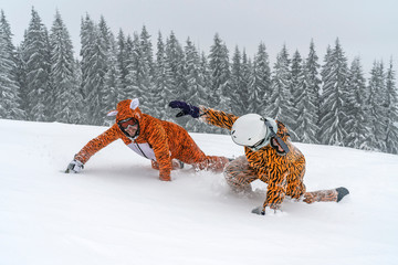 Happy couple people in tiger costumes have fun and enjoy the fresh snow in winter mountains Carpathians.