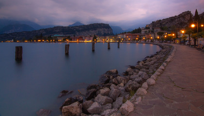 Obraz premium panoramic city lake view of torbole at blue hour; evening long term exposure of lake garda (lago di garda,italy)