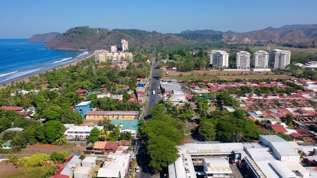 Aerial: Jaco Cityscape, Long Main Road Running Through City Towards Mountains and Parallel to the Beach