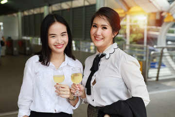 Successful asian businesswoman holding glasses of champagne with smiling while celebrating outdoor