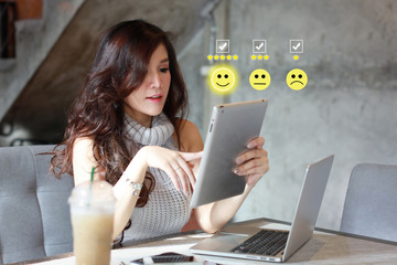 Beautiful asian woman in casual dress pressing smiling face and five stars emoticon on tablet for...