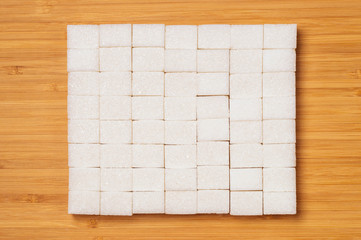 refined sugar is laid out in a square on a wooden background, mock-up, space for text, tinted image, selective focus