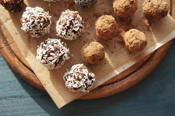 Homemade healthy energy vegan raw sweet balls made of dried fruits and nuts on wooden plate. Dessert with no added sugar, healthy diet food concept. Selective focus. Top view, flat lay.         