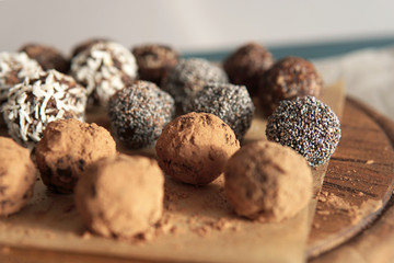 Homemade healthy vegan raw sweet balls made of dried fruits and nuts on wooden plate. Diet dessert with no added sugar, healthy diet gluten free food concept. Selective focus.         