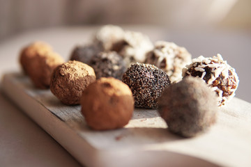 Homemade healthy vegan raw sweet balls made of dried fruits and nuts on wooden plate. Diet dessert with no added sugar, healthy diet gluten free food concept. Selective focus.         