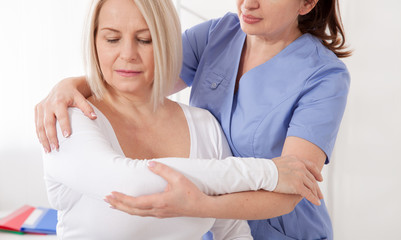 Fototapeta premium Physiotherapist working with middle aged patient in clinic
