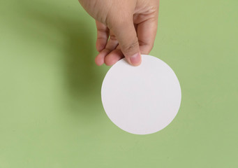 Fototapeta na wymiar Woman hand holding white circle paper. Isolated in green background.