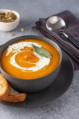 Pumpkin soup with cream on grey stone background. Copy space.