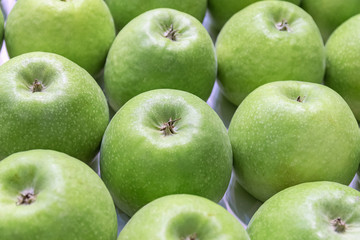 The ripe green apples stacked in a row