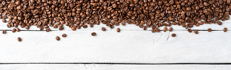 Overhead shot of roasted coffee beans on rustic wooden background with copyspace. Banner