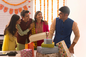 Colleagues standing together in office with gift boxes in front on the occasion of Diwali. 	