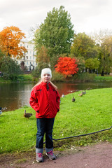 Obraz premium Girl is walking in the Park in autumn and she is standing on the shore of a pond with ducks