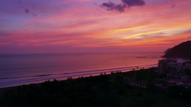 Aerial: Gorgeous Tropical Sunburst Sunset With Silhouette of Jaco and Mountains