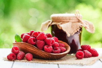 Fresh picked raspberries in basket and bowl on wooden rustic table. Homemade jam or marmelade from...