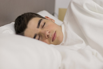 Obraz na płótnie Canvas portrait of young teenage man sleeping in bed