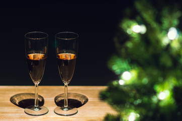 Two glasses of Rose wine on wooden table with Christmas tree and dark background.