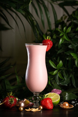 strawberry milkshake in a tall glass decorated with a flower