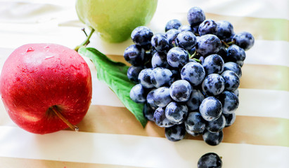 Three fruits, apples, guava, grapes are placed on the table.