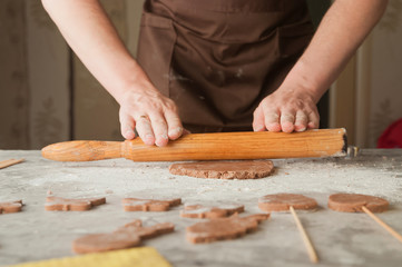 Men's hands and dough close-up. Baking gingerbread Christmas and Easter gingerbread cookies. A man in the kitchen is preparing cookies in an apron and copy space.