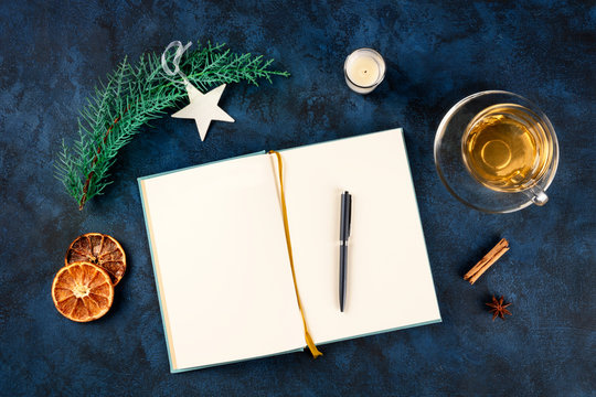 New Year resolutions, flatlay top shot with a place for text, on a dark blue background with Christmas decorations, a pen, and a cup of tea
