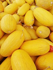 Bright juicy melon close-up. Yellow oblong melons on counter of bazaar or greengrocer. Selective focus image.