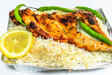 top view of delicious tasty chicken barbecued on the top of white rice and green fresh lemon slices in a white plate 