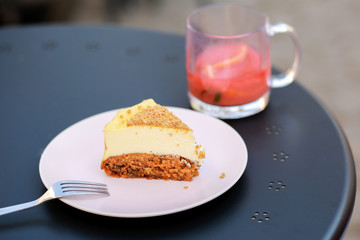  Classic simple New York cheesecake, closeup, selective focus Cheesecake on a summer playground on the table. Carrot sponge cake with cheese filling. Dessert in a cafe on the street with tea.