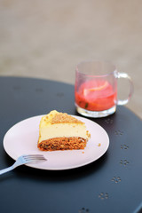  Classic simple New York cheesecake, closeup, selective focus Cheesecake on a summer playground on the table. Carrot sponge cake with cheese filling. Dessert in a cafe on the street with tea.