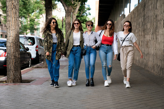Five female friends walking in the street