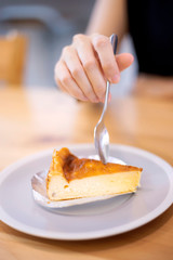 Hand woman holding spoon for eating homemade cheesecake. 