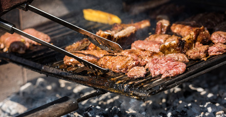 Beef meat with polenta and sausages cook on the barbecue flame, viewed from above