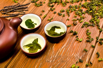 Chinese green oolong tea tieguanyin in the ceramic cups on a wooden background. 