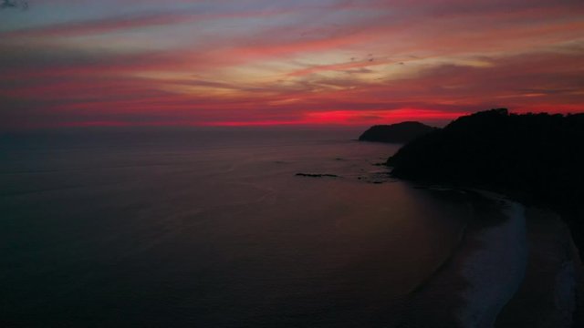 Aerial: Blood Orange Beach Sunset Near Mountain Silhouette and Dimly Lit Beach - Jaco, Costa Rica