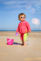 pretty little girl playing on the beach and protected from the sun