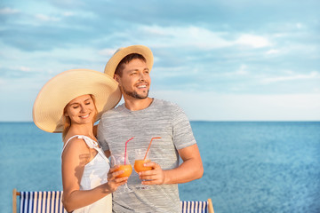 Portrait of happy couple with cocktails on sea beach