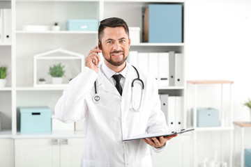 Portrait of male doctor talking by phone in clinic