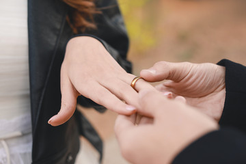 Obraz na płótnie Canvas Happy man putting wedding ring on his fiancee's finger outdoors, closeup