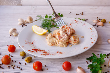 fried shrimp in cream sauce on a white plate on a light wooden background