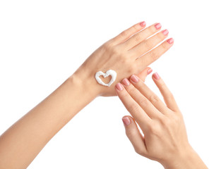 Heart made with cream on hand of young woman against white background